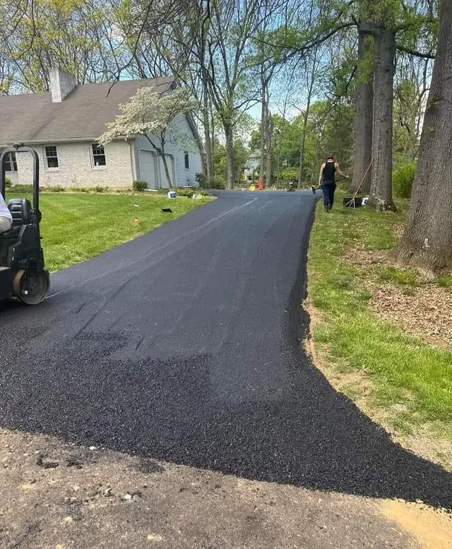 Completed asphalt driveway beside a home