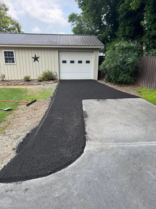 Fresh asphalt driveway to a detached garage