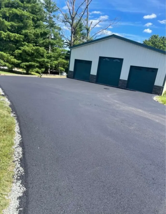 Wide asphalt driveway to an outbuilding