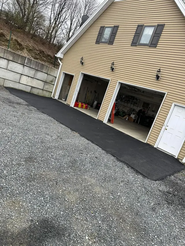 New asphalt driveway leading to a two-car garage